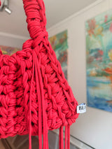Bright red crochet shoulder bag with a braided top handle and long side ties