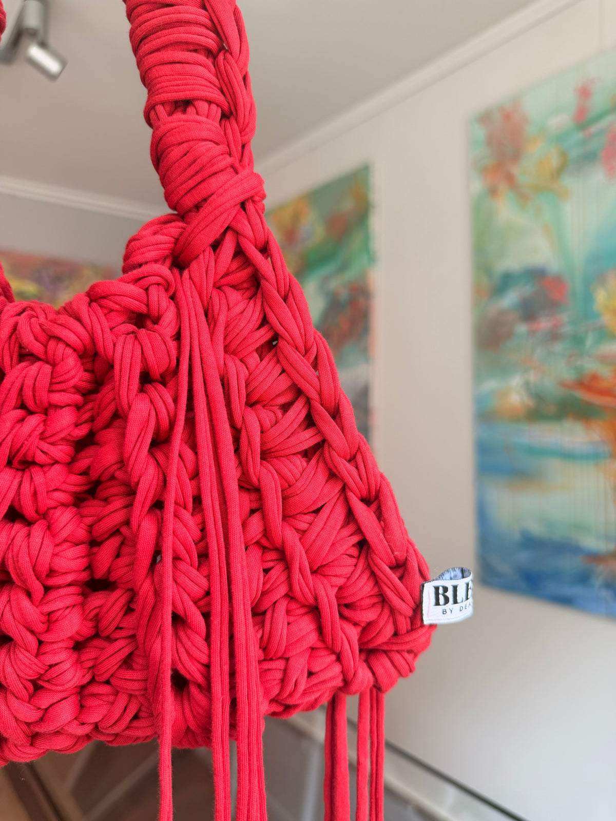 Bright red crochet shoulder bag with a braided top handle and long side ties