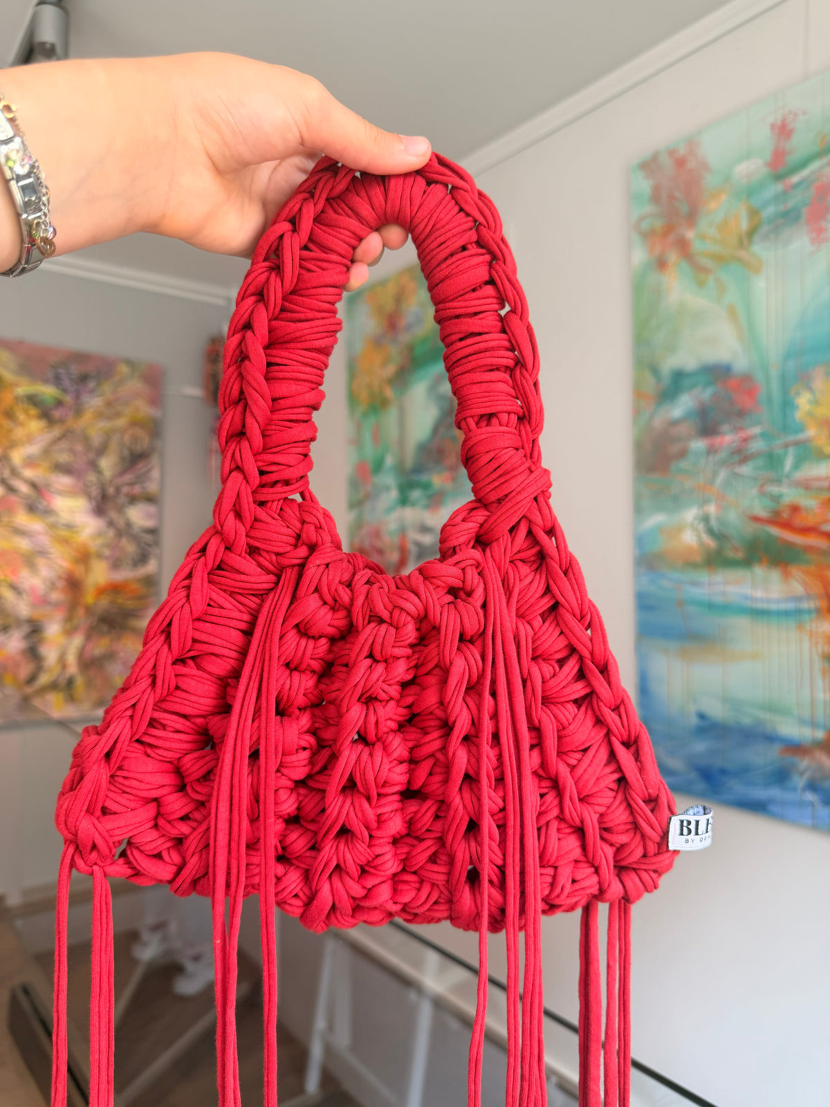 Bright red crochet shoulder bag with a braided top handle and long side ties