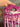Deep magenta crochet bag banded with blush and cream, with a braided top handle and long fringe