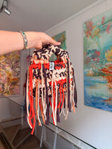 Bright orange crochet bag banded with cocoa, cream and apricot, with a braided top handle and long fringe