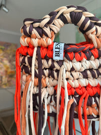 Bright orange crochet bag banded with cocoa, cream and apricot, with a braided top handle and long fringe