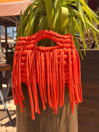 Bright orange crochet bag with a chunky braided top handle and a long fringe