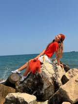 Bright orange crochet bag with a chunky braided top handle and a long fringe