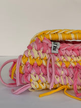 Pink and marigold ties knotted through the stitch on the Marigold and Rose crochet clutch