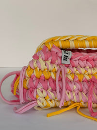Pink and marigold ties knotted through the stitch on the Marigold and Rose crochet clutch