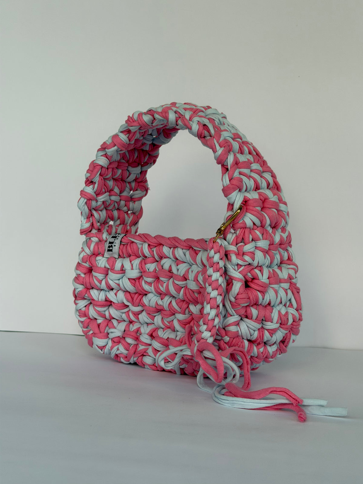 Pink and pale blue crochet shoulder bag with a big rounded handle, gold clasp and long ties