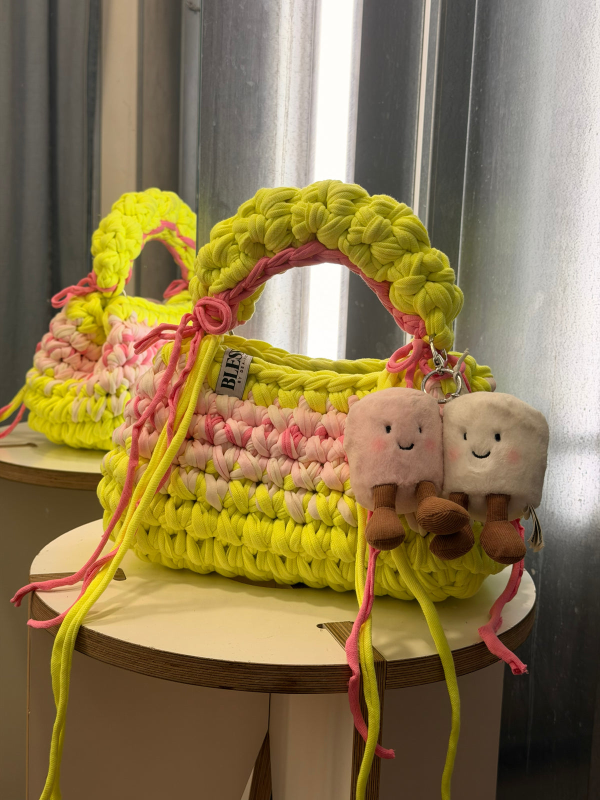 Neon yellow bobble-stitch crochet bag banded with blush, with a chunky top handle and bows